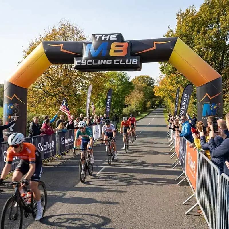 Cyclists riding under inflatable archway