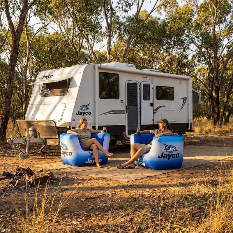 People sitting in inflatable chairs outside caravan